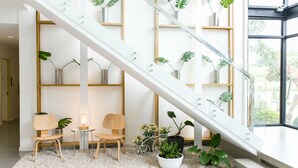 Un intérieur moderne avec un escalier en verre, des chaises en bois et des plantes en pot.