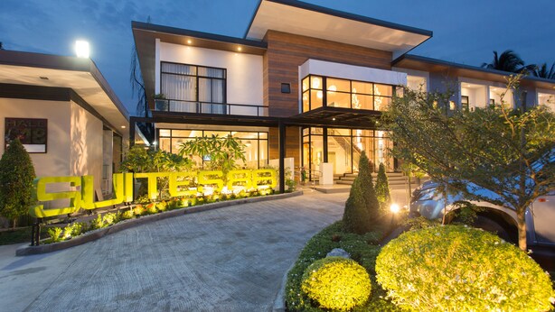 Un hôtel moderne doté d'une entrée bien éclairée, d'une enseigne bien visible indiquant « SUITE » et d'une allée aménagée.