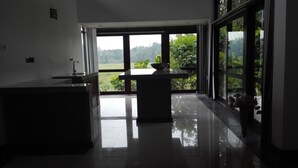 Una cocina moderna con una isla grande, vistas a un jardín exuberante a través de amplios ventanales y un suelo limpio y reflectante.
