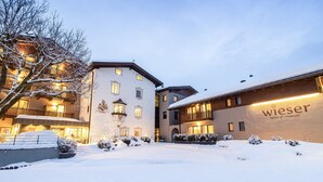 A hotel with a snow-covered courtyard, illuminated windows, and a sign reading "wieser home of emotions." - Hotel Wieser (Campo di Trens)