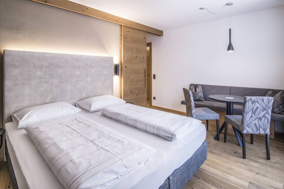 Een moderne hotelkamer met een groot bed, een klein tafeltje en een bank.