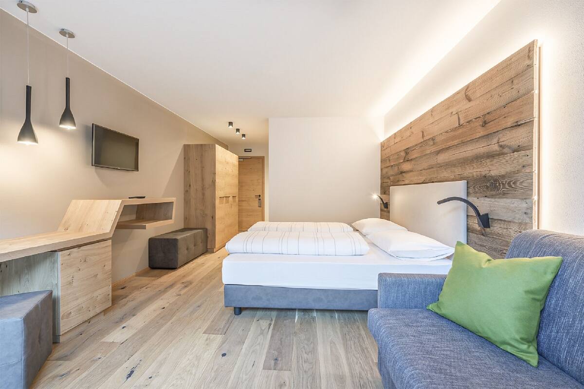 Een moderne slaapkamer met een bed, een bank, een bureau en een televisie.