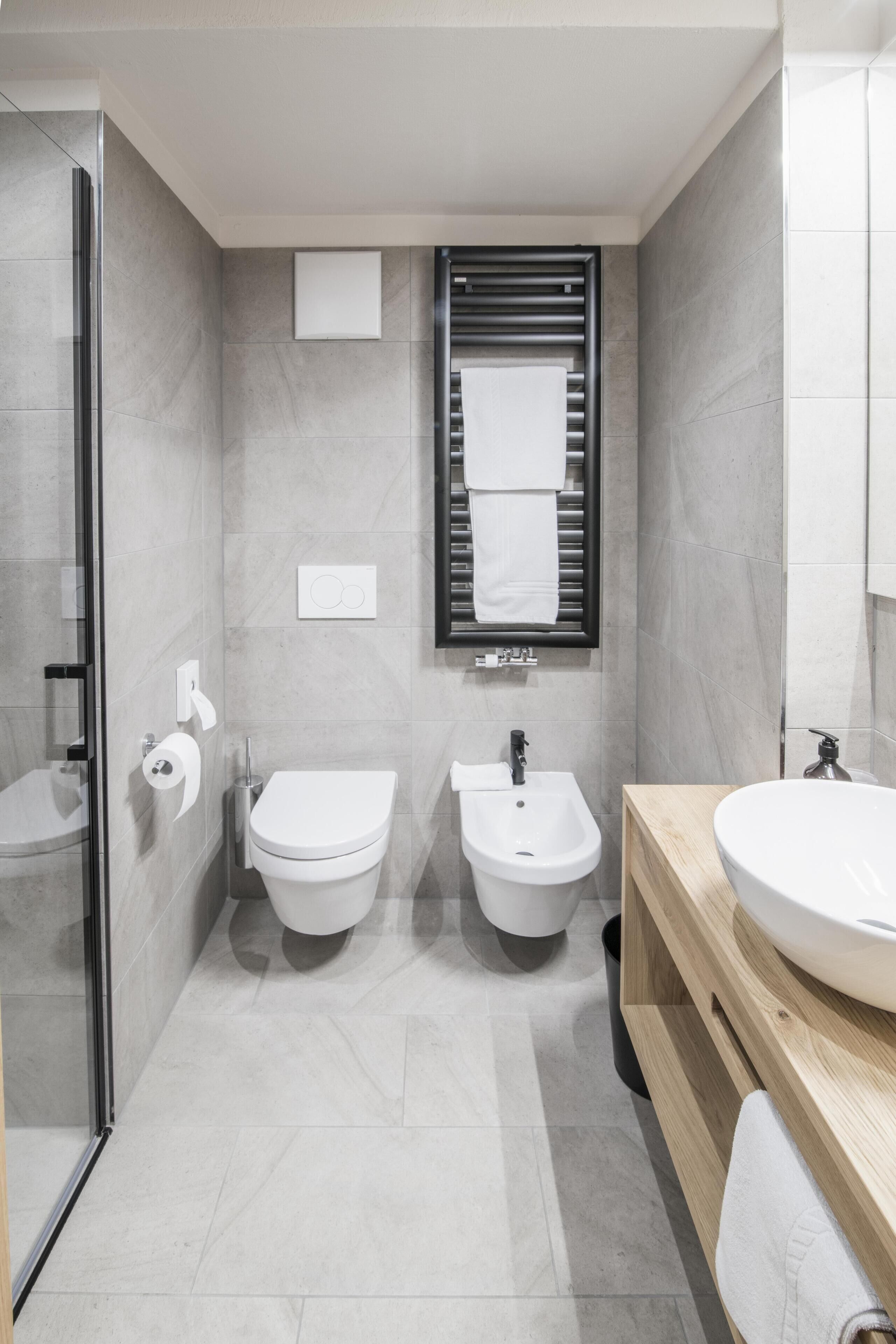 Un baño moderno con cabina de ducha de vidrio, inodoro, bidé y tocador con lavamanos.