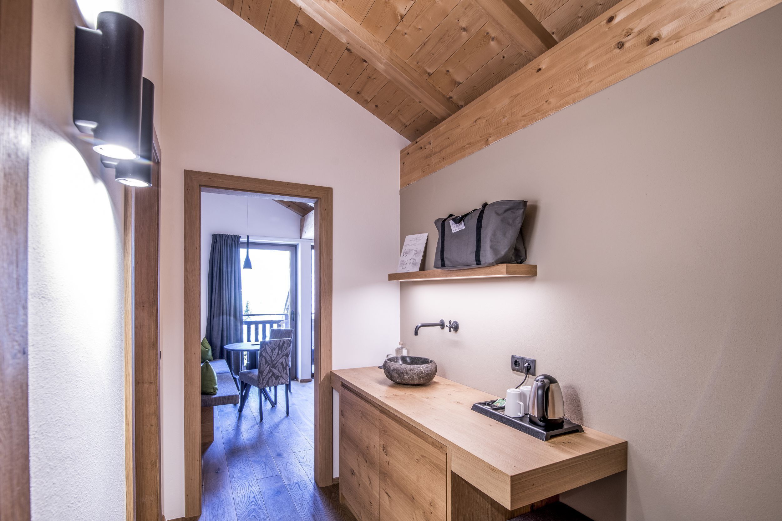 A modern bathroom with a wooden vanity, a sink with a stone basin, and a towel rack.