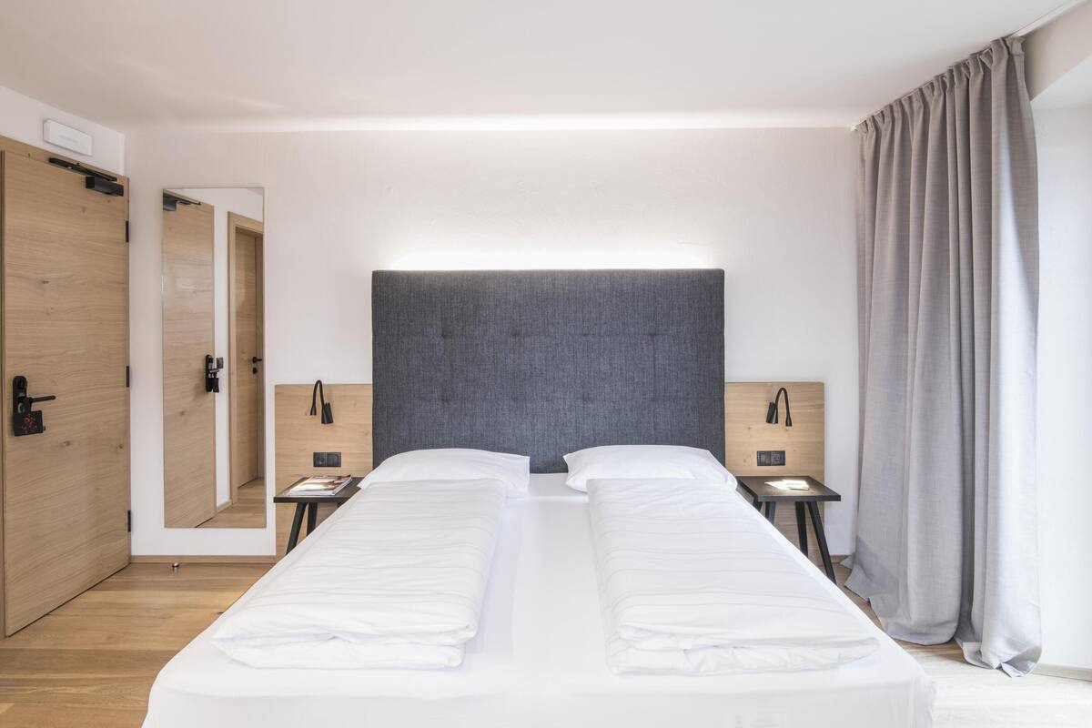 Een moderne hotelkamer met een groot bed, nachtkastjes, een spiegel en een kledingkast.