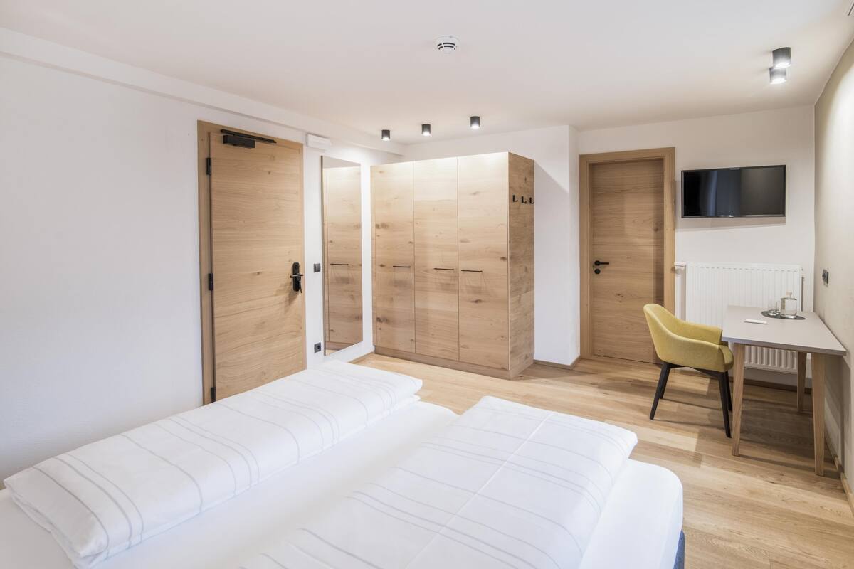 Een moderne slaapkamer met een groot bed, een bureau, een stoel en een televisie.