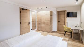 Una camera da letto moderna con un letto grande, una scrivania, una sedia e una TV.