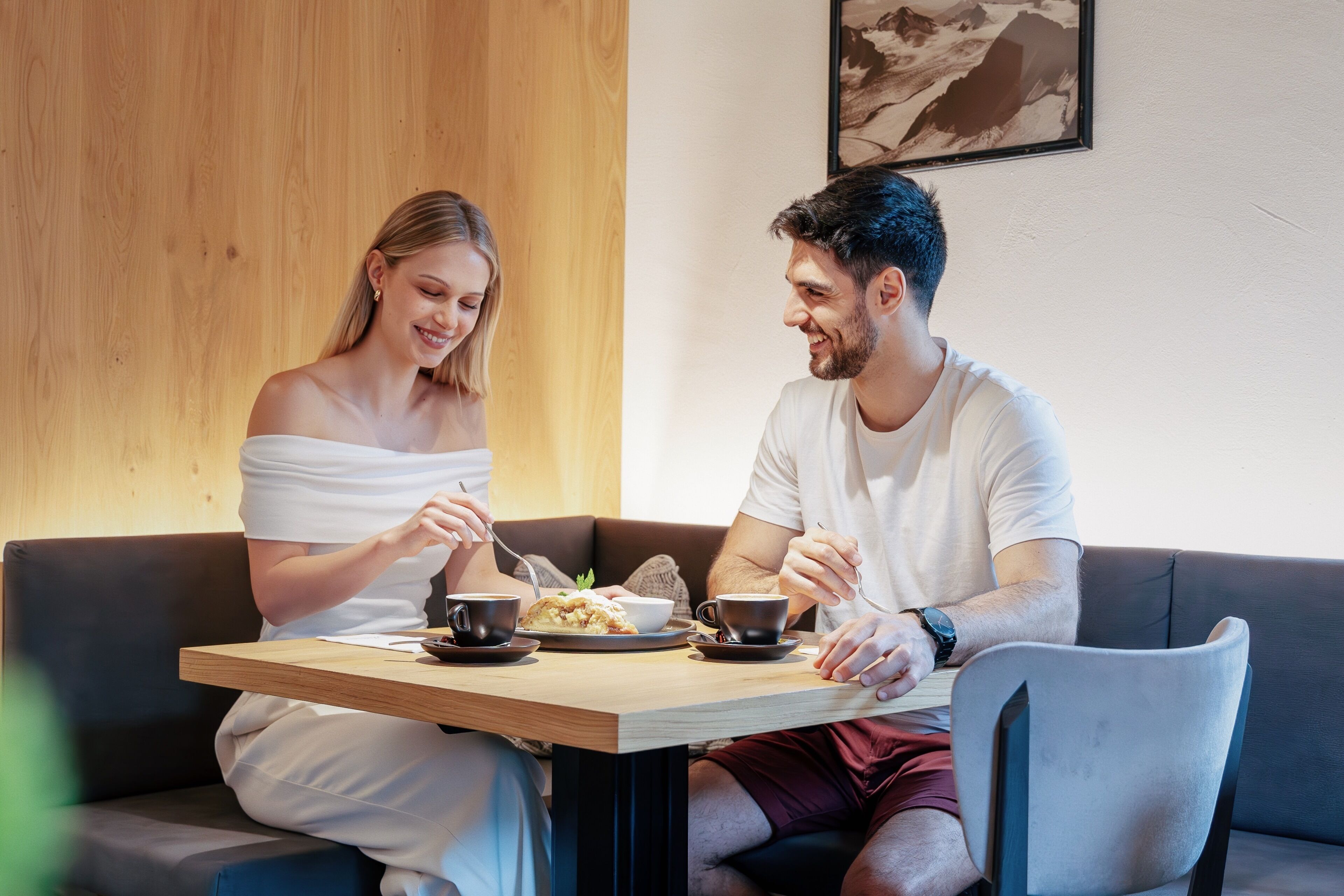 Una pareja cenando en una mesa de madera con vistas a un paisaje montañoso.