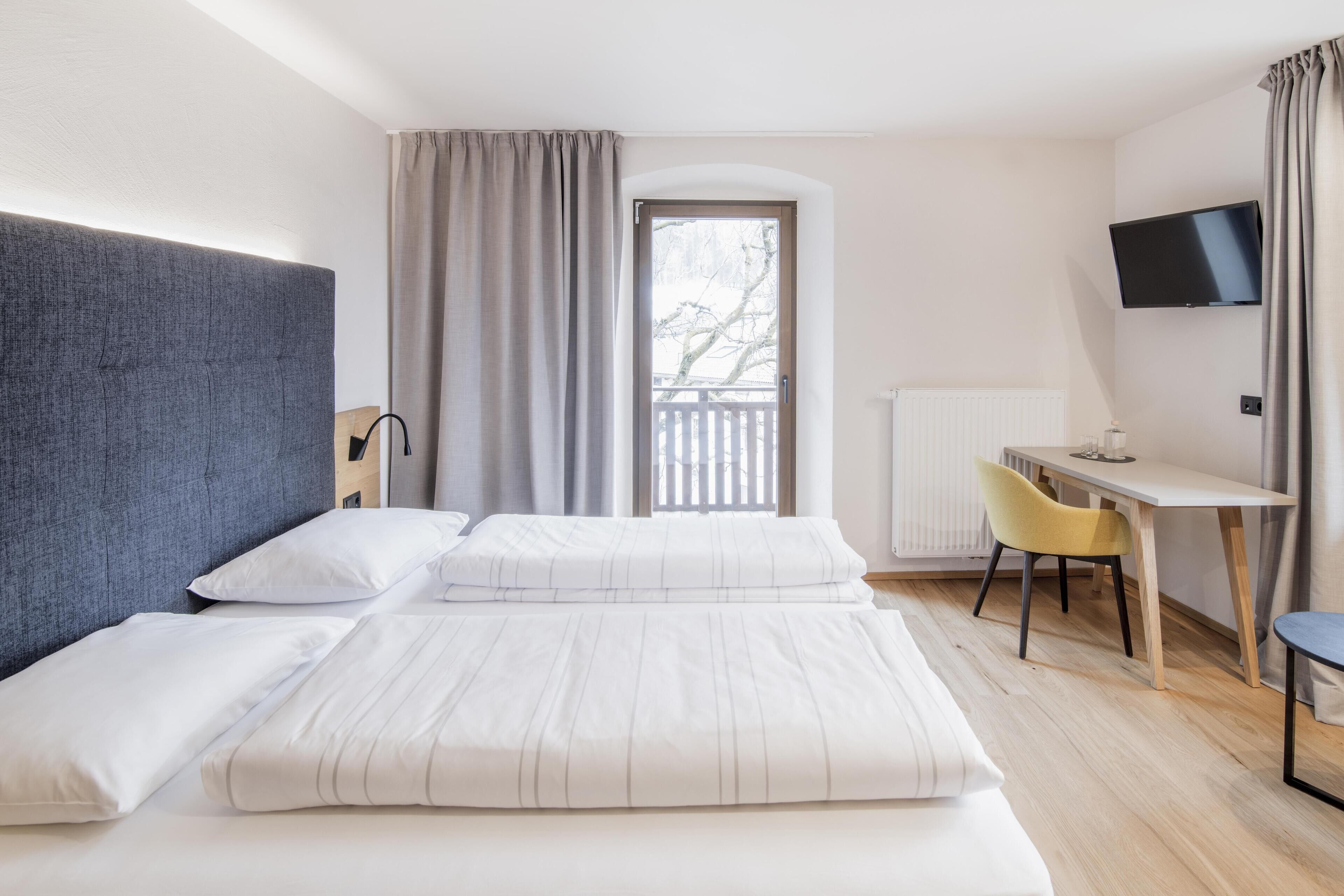 Una habitación de hotel moderna con una cama grande, un escritorio y un televisor.