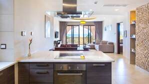 Una cocina moderna con una isla central, electrodomésticos integrados y vistas al exterior.