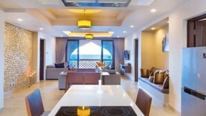 Una sala de estar moderna con comedor, cocina y vista al mar.