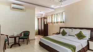 Une chambre d’hôtel équipée d’un lit, d’une chaise, d’une petite table et d’un appareil de climatisation.