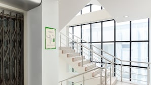 Un intérieur moderne avec un escalier, de grandes fenêtres et une rambarde en métal.