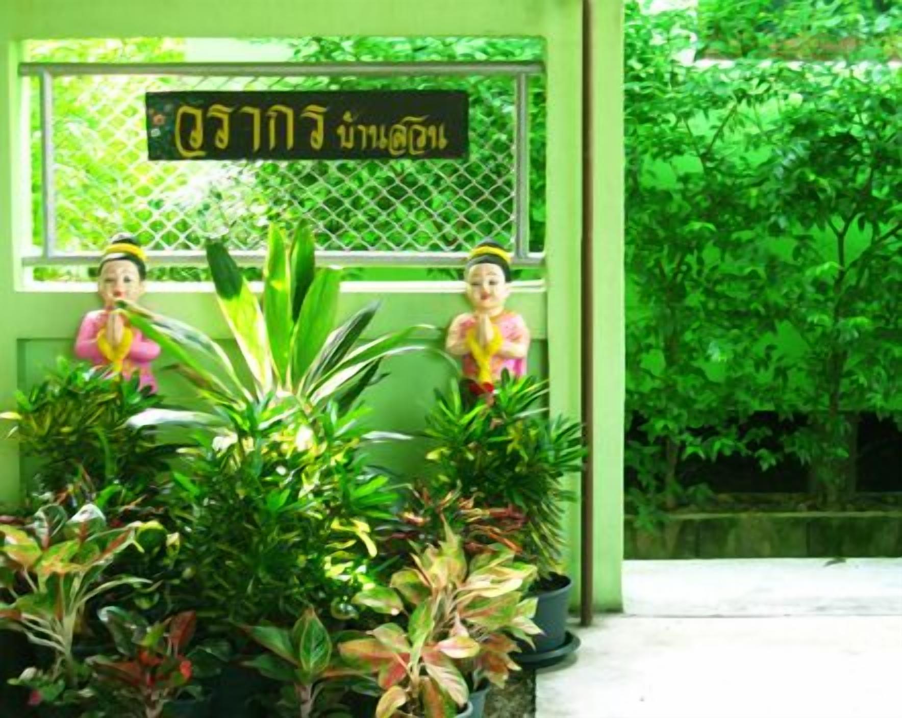 A green building with two statues and a sign in a foreign language.