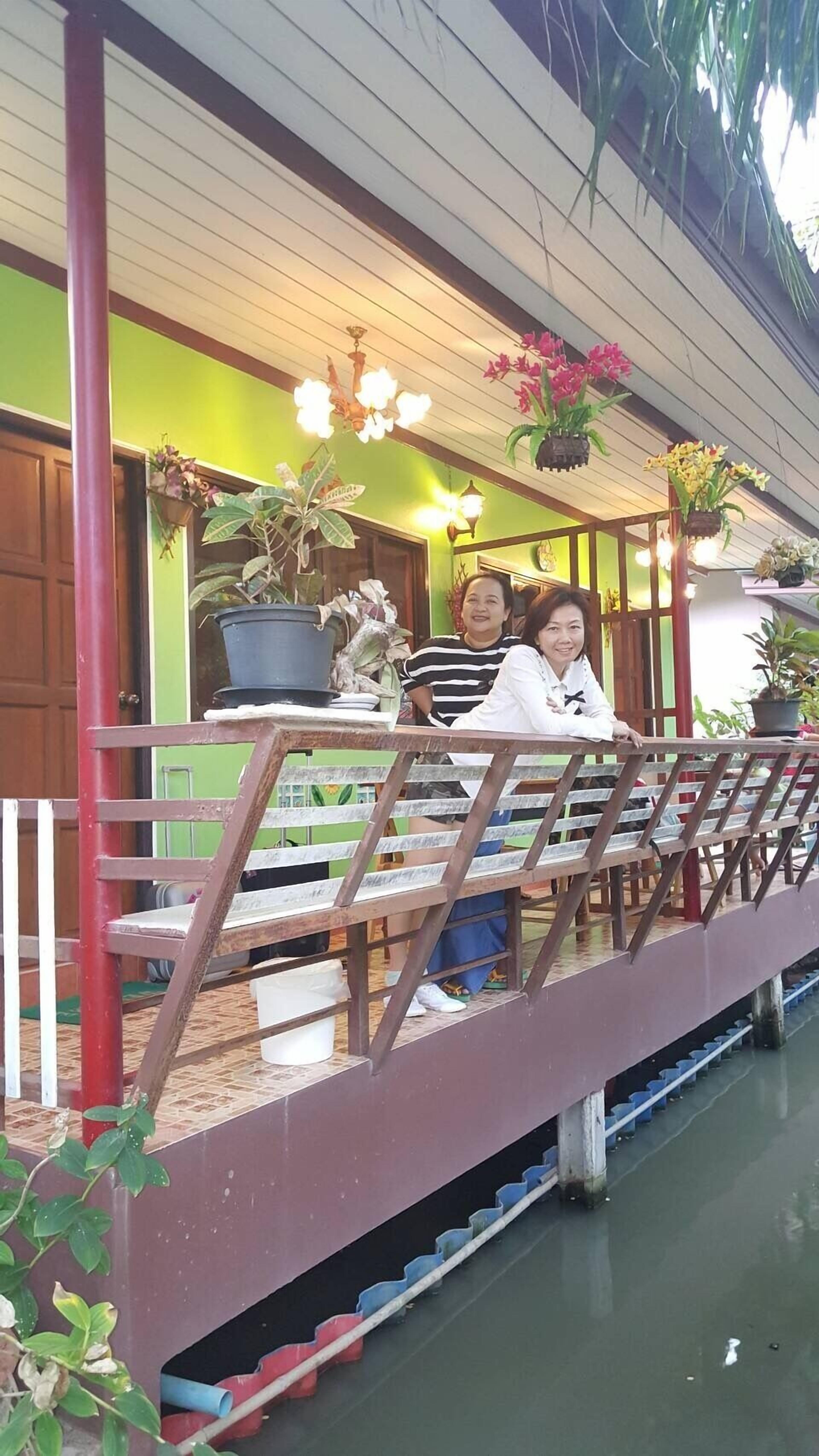 A covered outdoor seating area with a railing, potted plants, and a view of the water below.