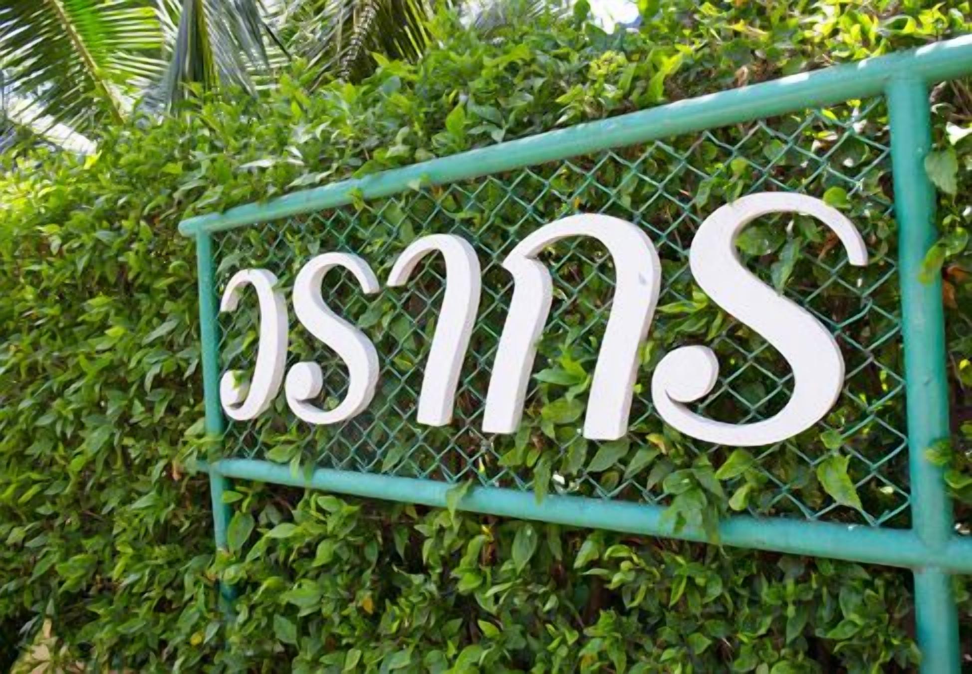 Une pancarte portant l’inscription « OSMS » est fixée à une clôture métallique verte.