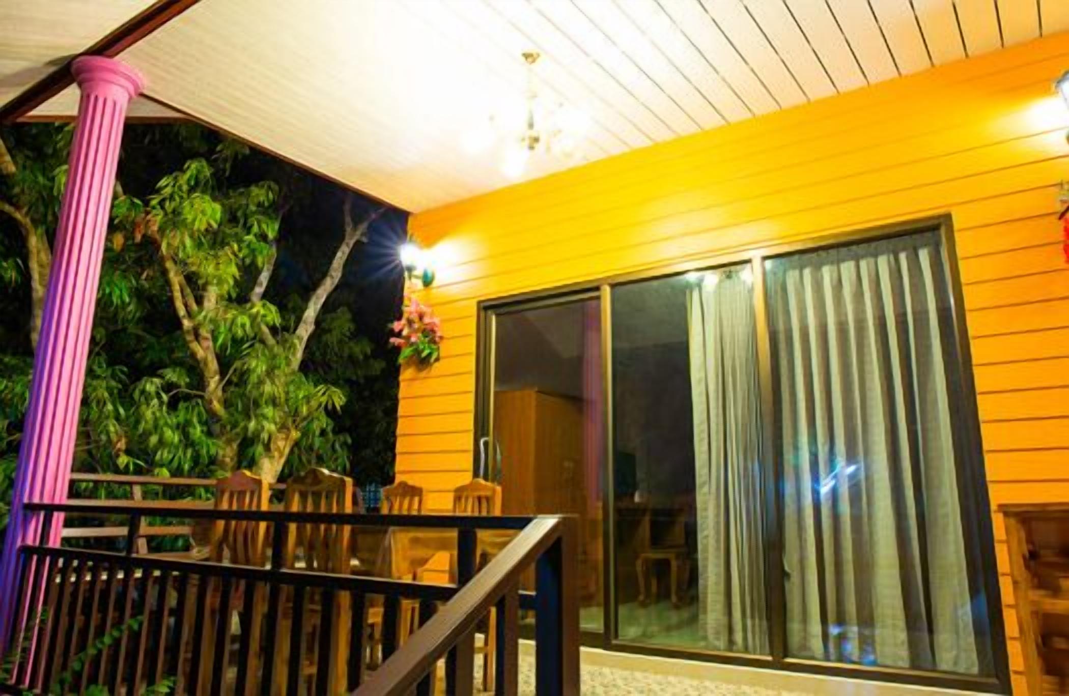 A covered outdoor area with a wooden deck, a staircase, and a large sliding glass door.