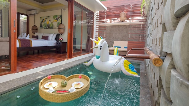 Un espace piscine agrémenté d’une licorne flottante, un coin repas aménagé et une chambre avec vue.