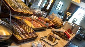A buffet with various food items including pastries, bread, and a cake. - Hotel Edenpark (Brunssum)
