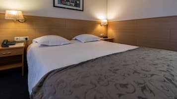 Ein Hotelzimmer mit einem Bett, zwei Nachttischlampen, einem Nachttisch mit Telefon und einem Bild an der Wand.