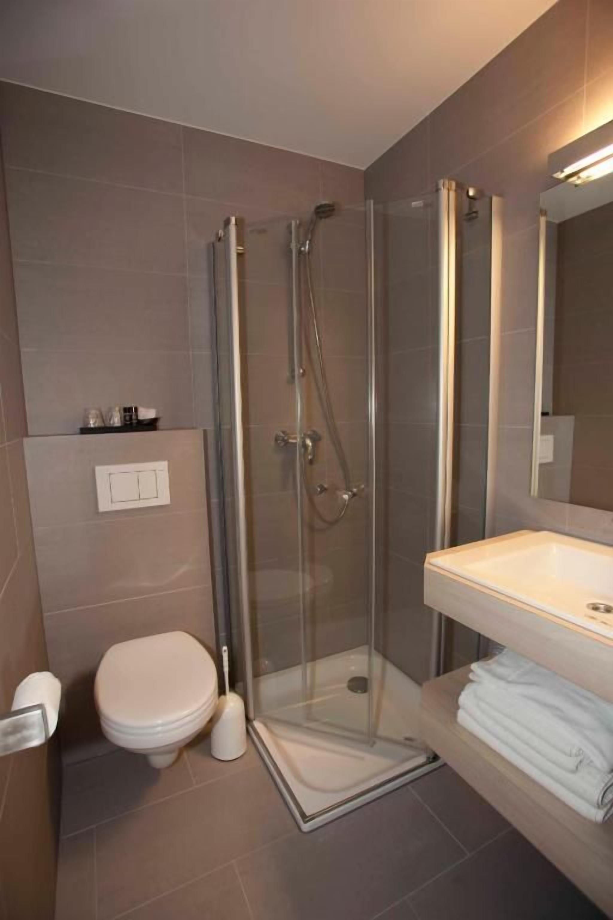 Un baño moderno con cabina de ducha de vidrio, inodoro y lavabo con espejo.