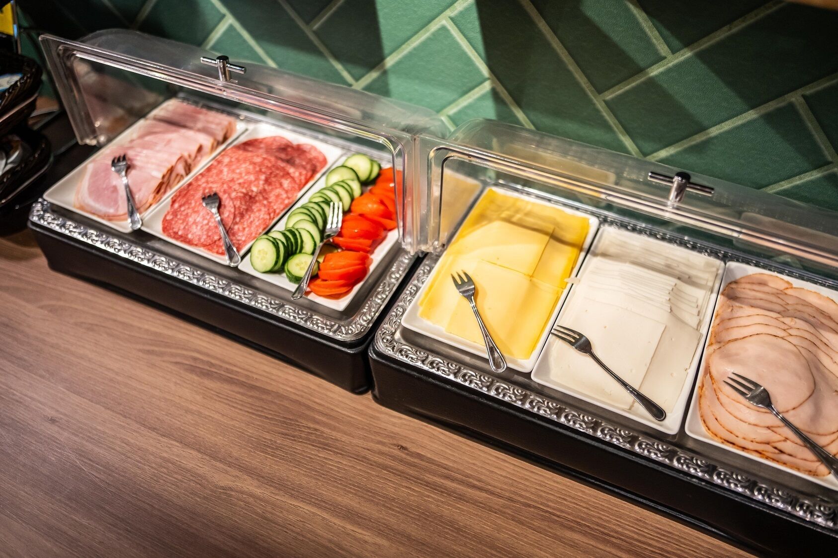 A buffet with various food items including meats, vegetables, and cheese.