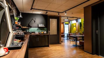A modern kitchen with a coffee machine, a fruit bowl, and a breakfast bar.