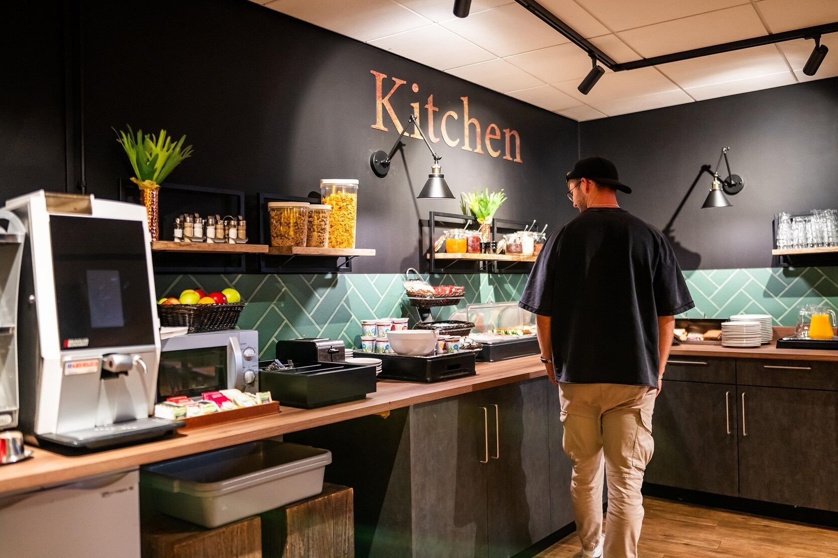Cocina moderna con un letrero que dice 'Kitchen', equipada con cafetera, tostadora y varios recipientes de comida.
