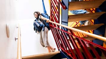 Eine Person steigt eine Holztreppe mit roten und blauen Geländern hinauf.