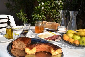 A table set with food and drinks, including bread, fruits, and a bottle of olive oil.
