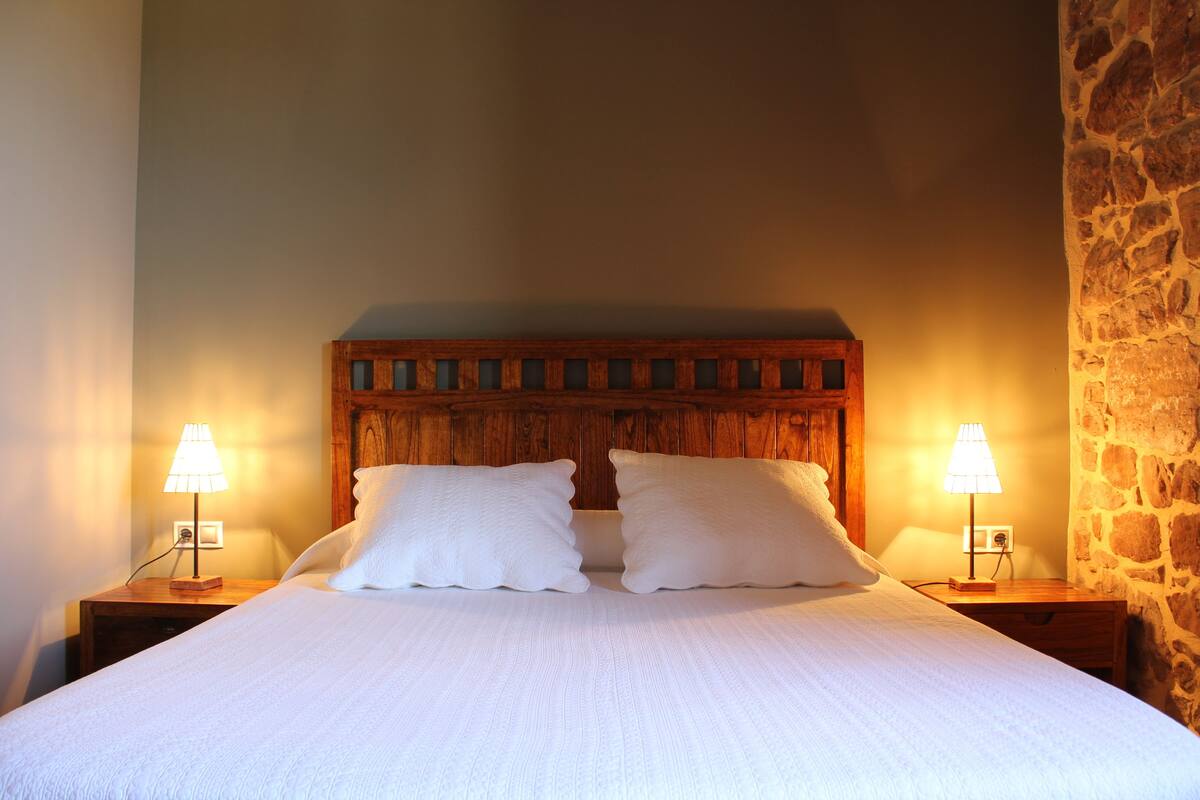 A neatly made bed with two pillows and two bedside lamps.