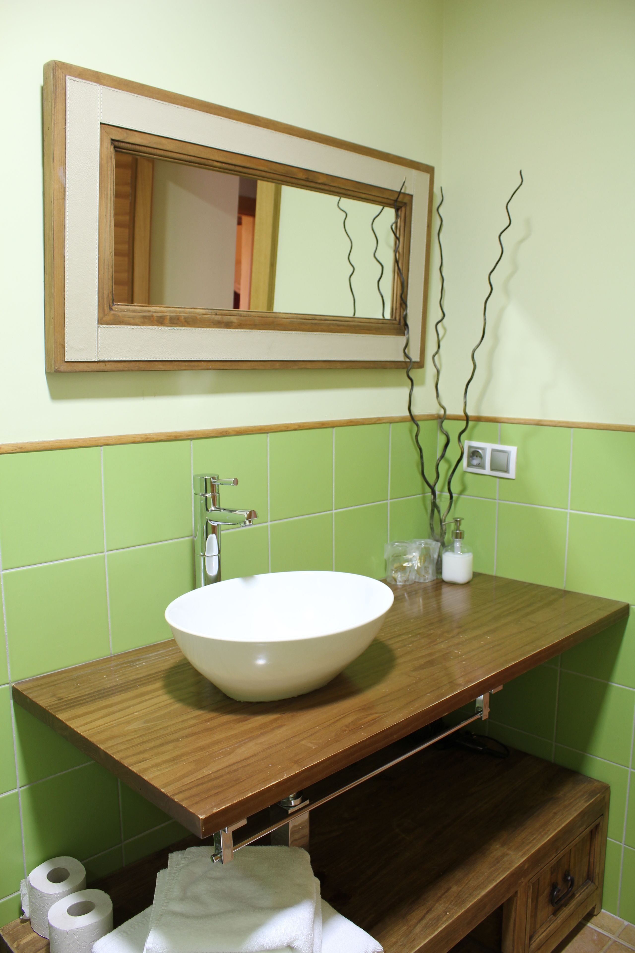 Un bany amb un moble de tocador de fusta, un lavabo blanc i un mirall a la part superior.