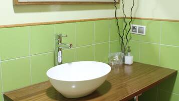 Un bany amb un moble de tocador de fusta, un lavabo blanc i un mirall a la part superior.