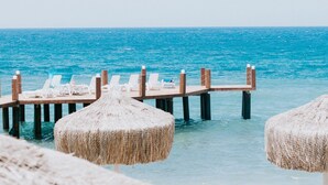 A wooden pier with lounge chairs and thatched umbrellas extending into the sea. - Faustina Hotel & Spa (Kusadasi)