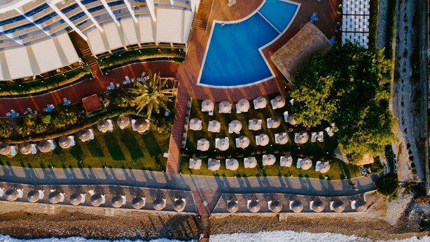 An aerial view of a cruise ship with a pool area, outdoor seating, and a pier extending into the water. - Faustina Hotel & Spa (Kusadasi)