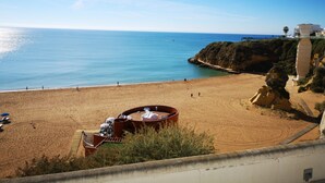 Una spiaggia con una struttura circolare, una scogliera e un edificio sullo sfondo.