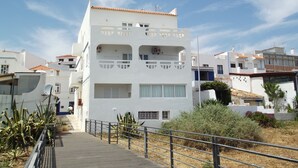 Un edificio bianco con balconi, un tetto in tegole e un vialetto lastricato.