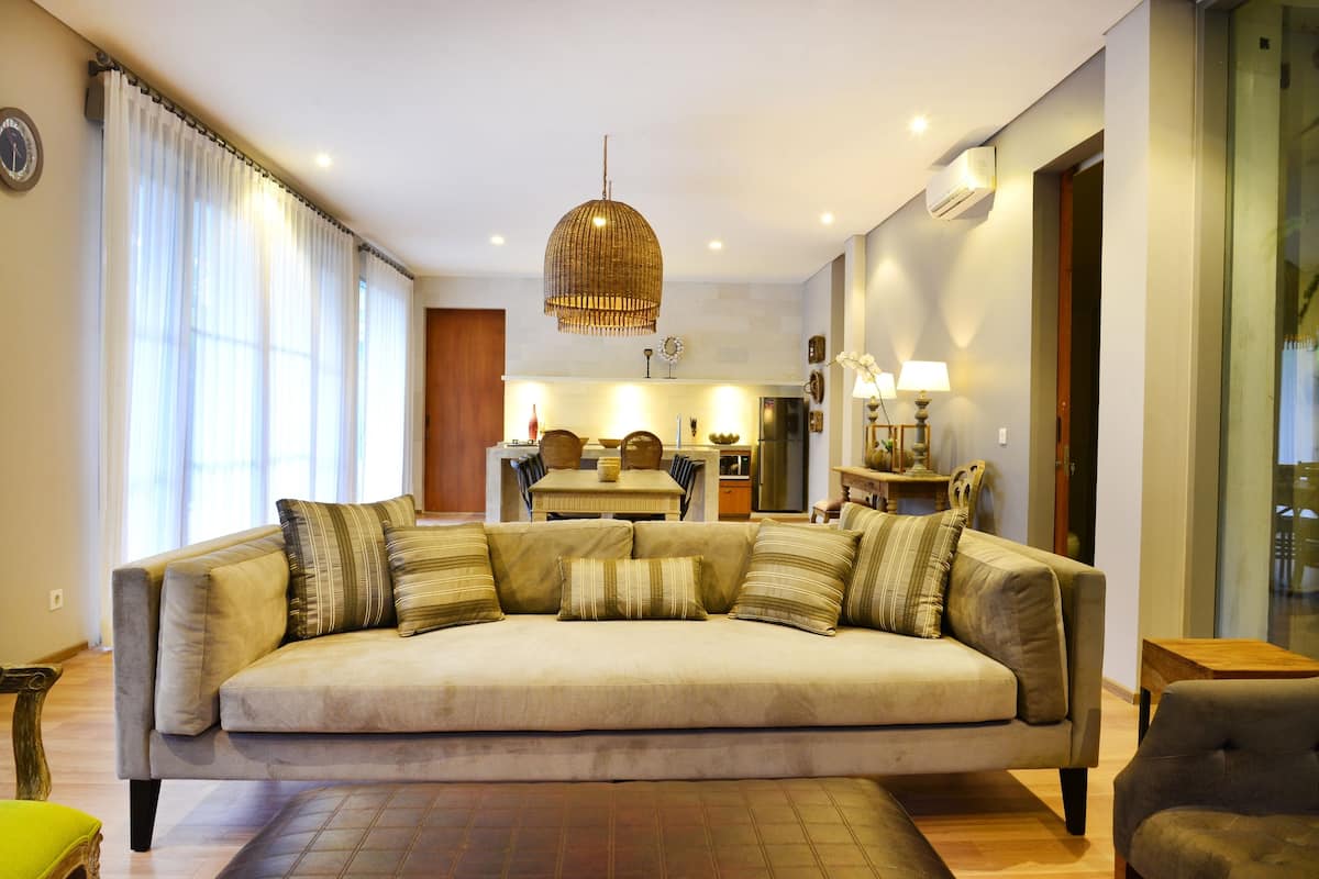 Una sala de estar moderna con un sofá, una mesa de comedor y una cocina al fondo.