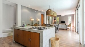 Une cuisine moderne dotée d’un îlot central, de meubles en bois et d’un coin repas avec des chaises et un téléviseur.