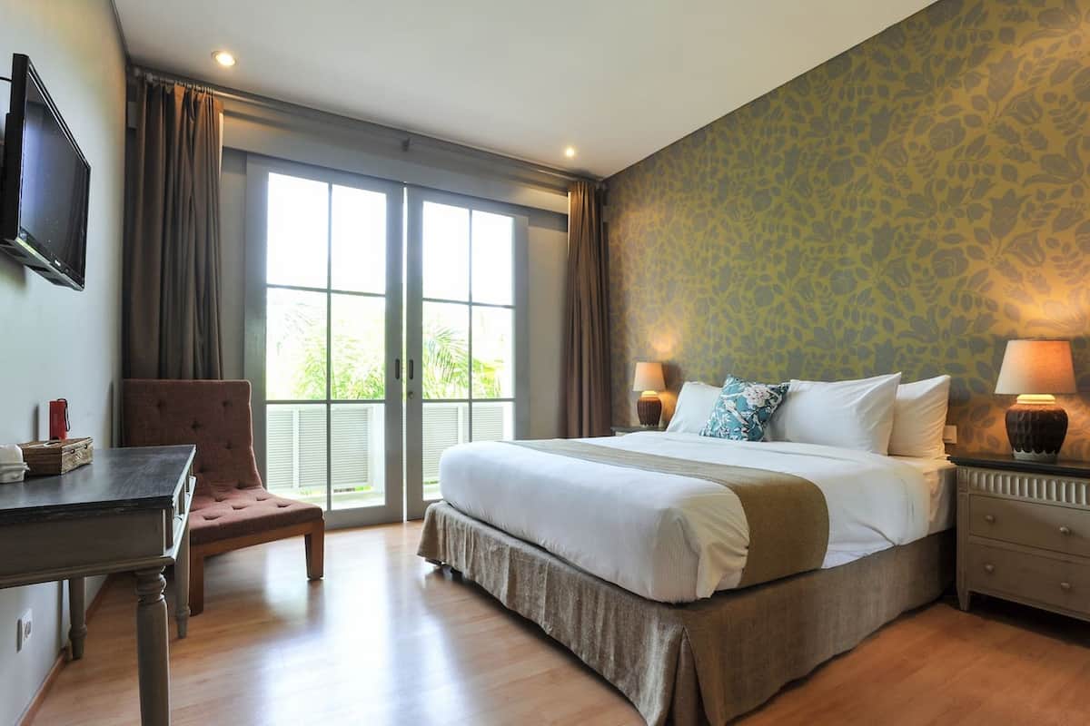 Una habitación de hotel con una cama grande, un escritorio, una silla y un televisor.
