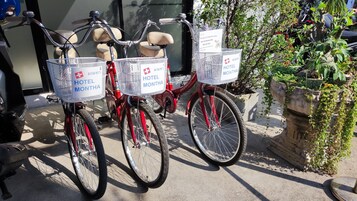 Dos bicicletas con cestas que indican "HOTEL MONTHA" estacionadas frente a un edificio.