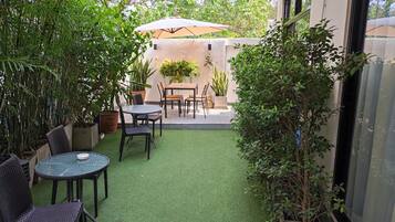 A patio with artificial grass, a table and chairs, and potted plants.