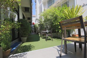 A courtyard with a wooden bench, potted plants, and a small table and chairs. - Montha Hotel (Chiang Mai)