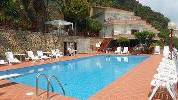 A swimming pool with white lounge chairs and a stone wall.