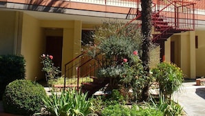 A building with a red-tiled roof, a central staircase, and a palm tree. - Residence Green Park (Ventimiglia)