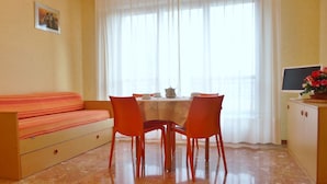 A room with a sofa, dining table, chairs, and a cabinet. - Residence Green Park (Ventimiglia)