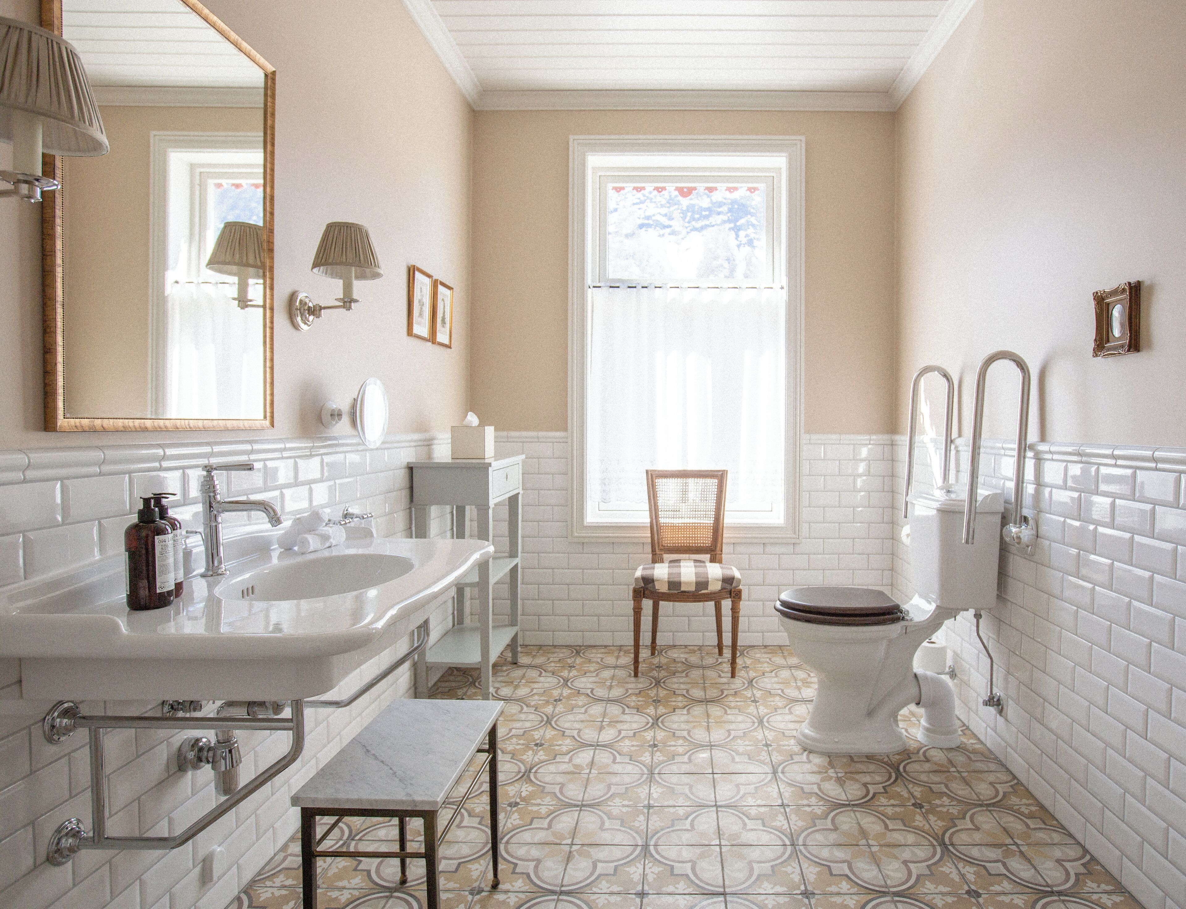 Ein Badezimmer mit zwei Waschbecken, einer Toilette, einem Stuhl und einem Fenster.