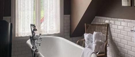A bathroom with a freestanding bathtub, a window with curtains, and a radiator.