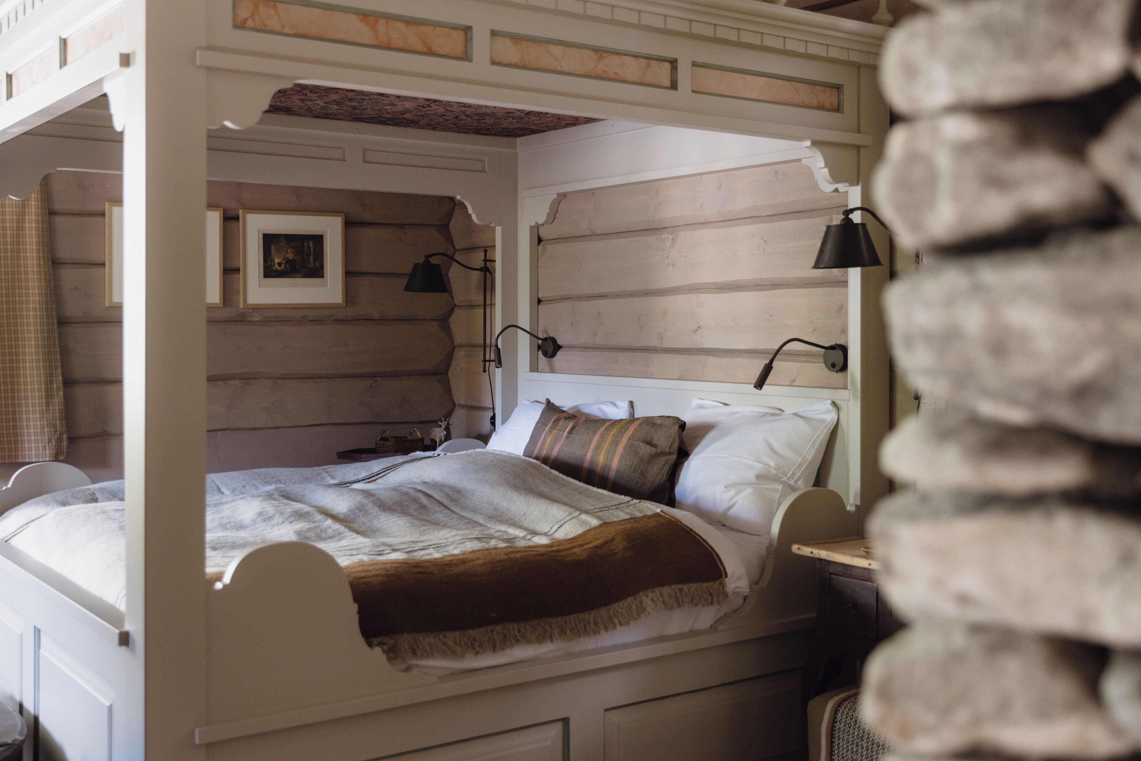 Un lit à baldaquin avec une tête de lit en bois, une table de chevet et une lampe.