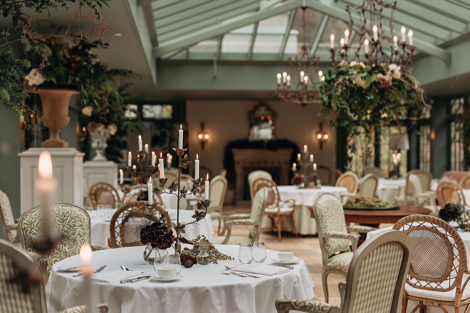 A formal dining room with round tables, white tablecloths, and candlelit centerpieces.